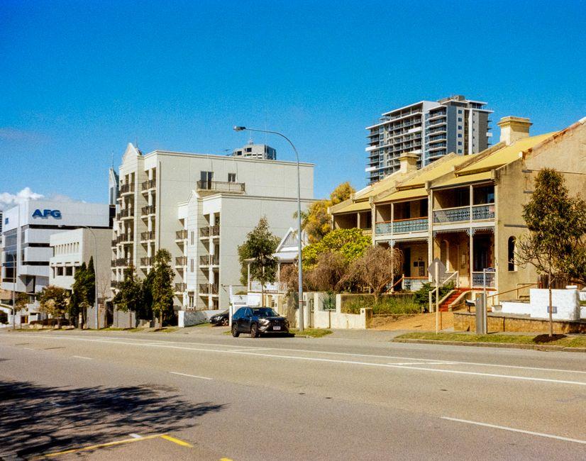 A Street with Many Buildings and Cars Parked on It
